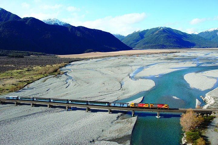 Experience the stunning landscapes of New Zealand’s South Island as the TranzAlpine train weaves through majestic mountains and serene rivers showcasing nature's grandeur at every turn.